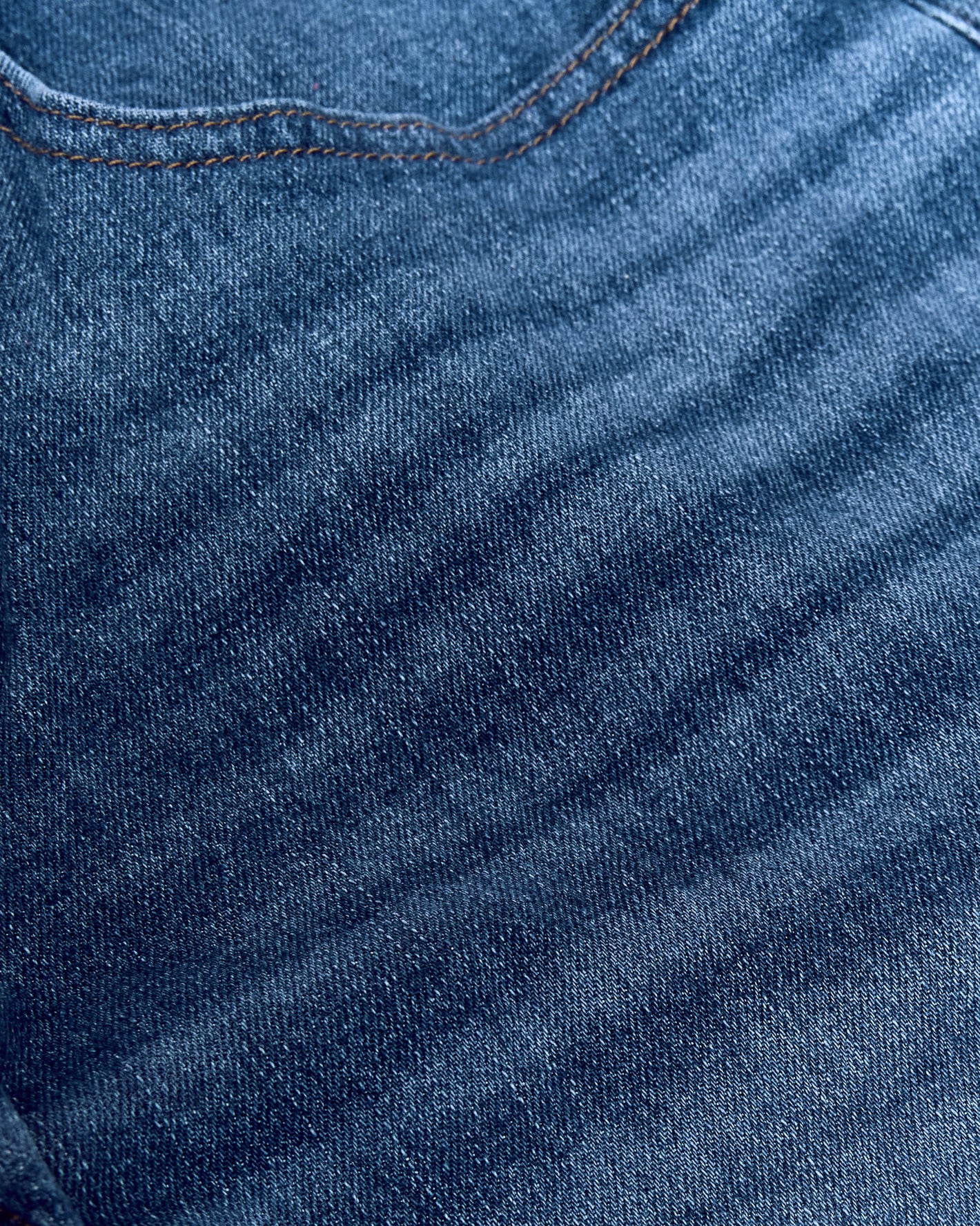 Medium Indigo Wash Straight Authentic Denim Jeans close-up, showcasing weave and orange stitching.