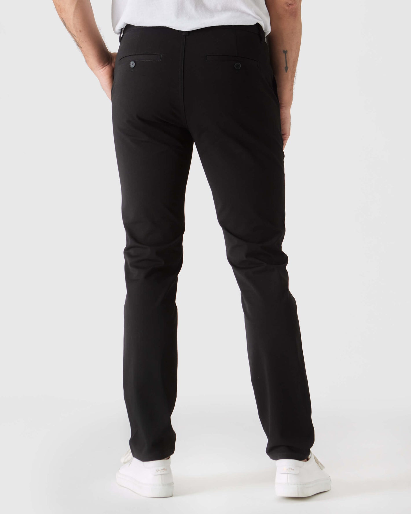 Black Slim Twill Chino Pant with stretch, buttoned back pockets, white sneakers.