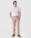 Man wearing Khaki Slim Twill Chino Pant with white polo and brown shoes.