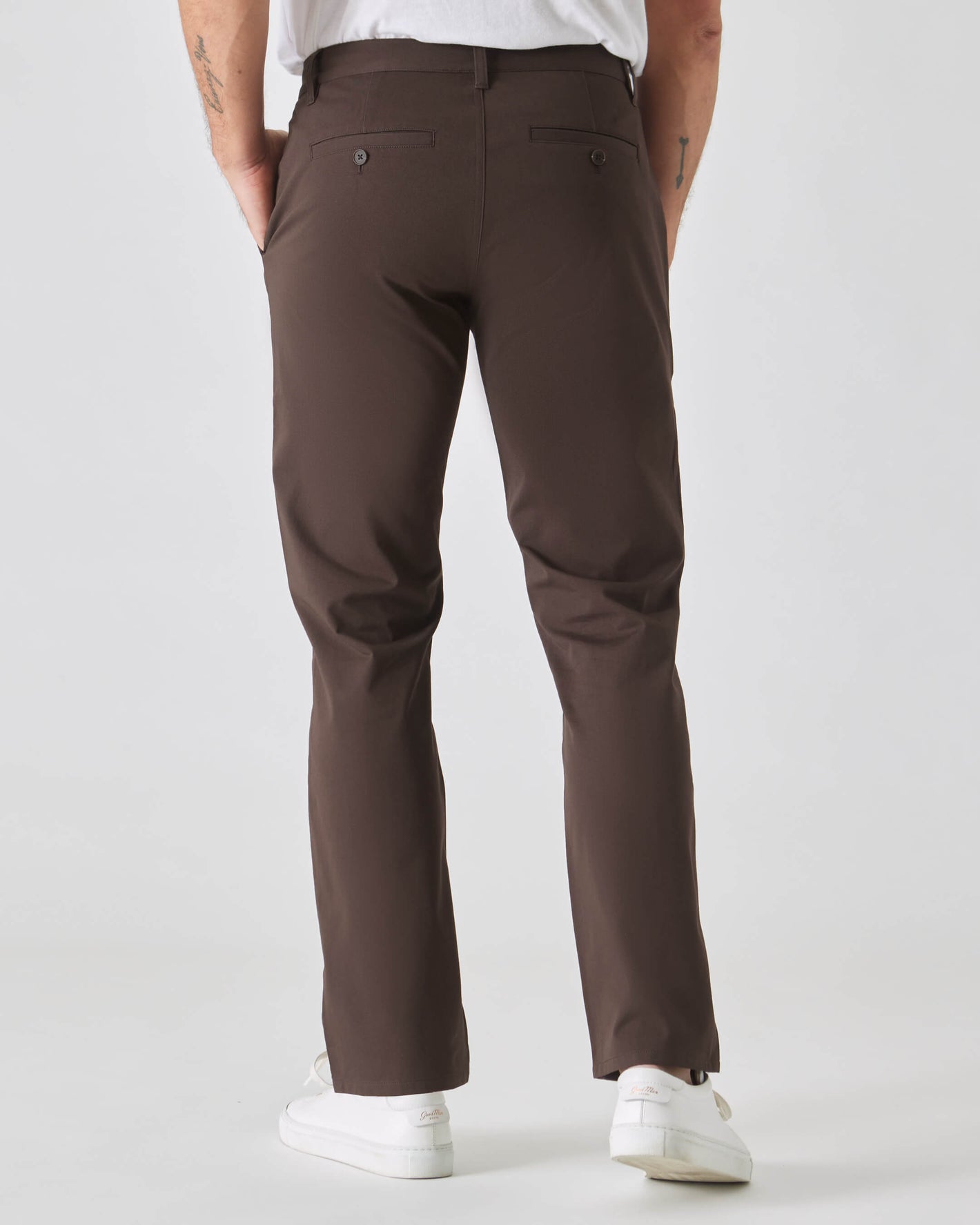 Dark Oak Straight Twill Chino Pant with white sneakers, hands in pockets.