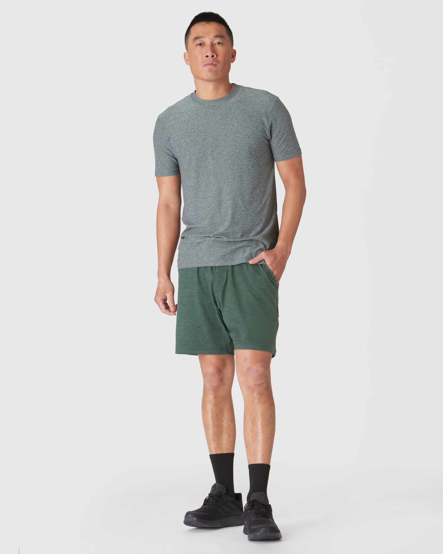 Man wearing Heather Forest Active Comfort Shorts with pockets, black socks, and shoes.