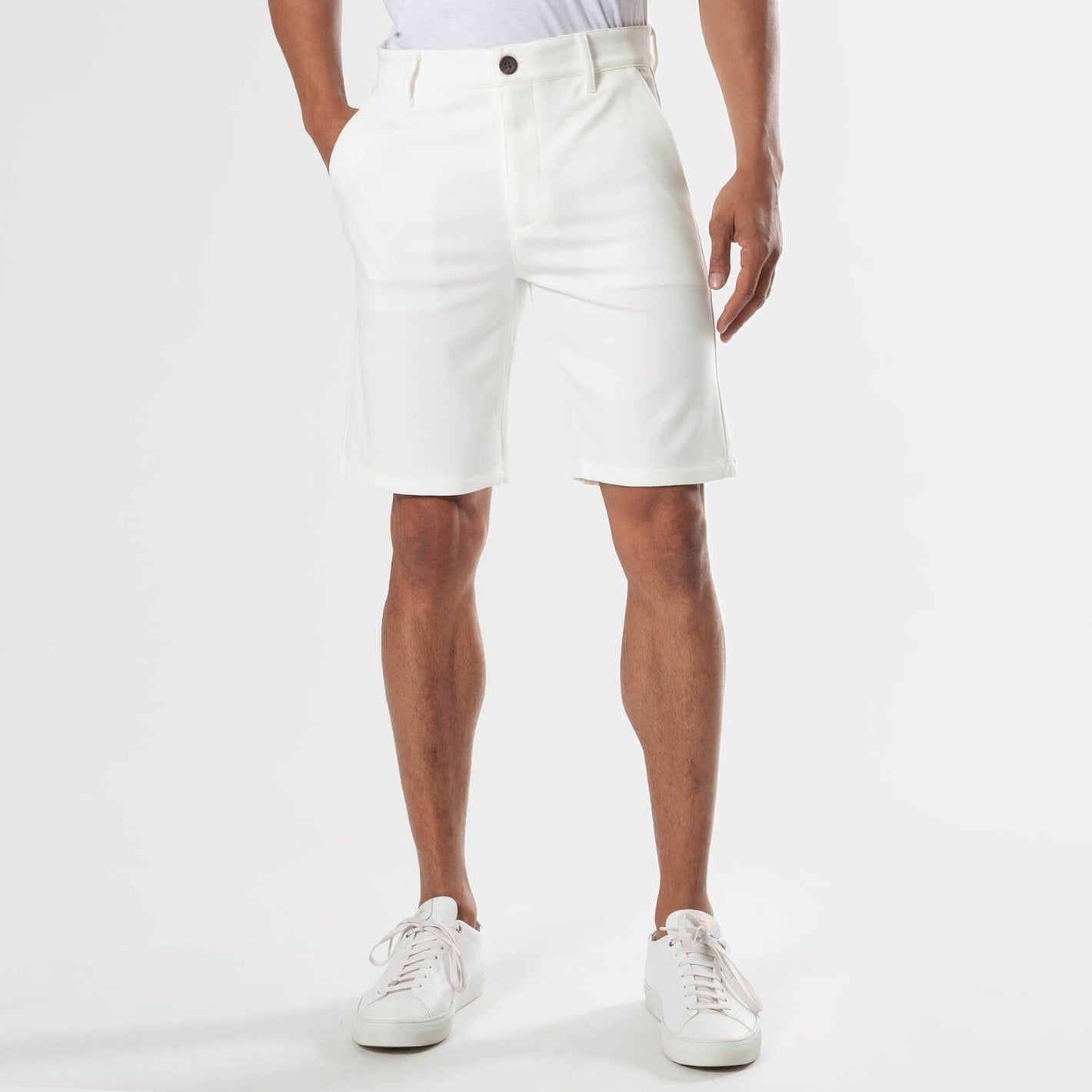 Ivory Neutral Chino Shorts with side pockets, belt loops, paired with sneakers.