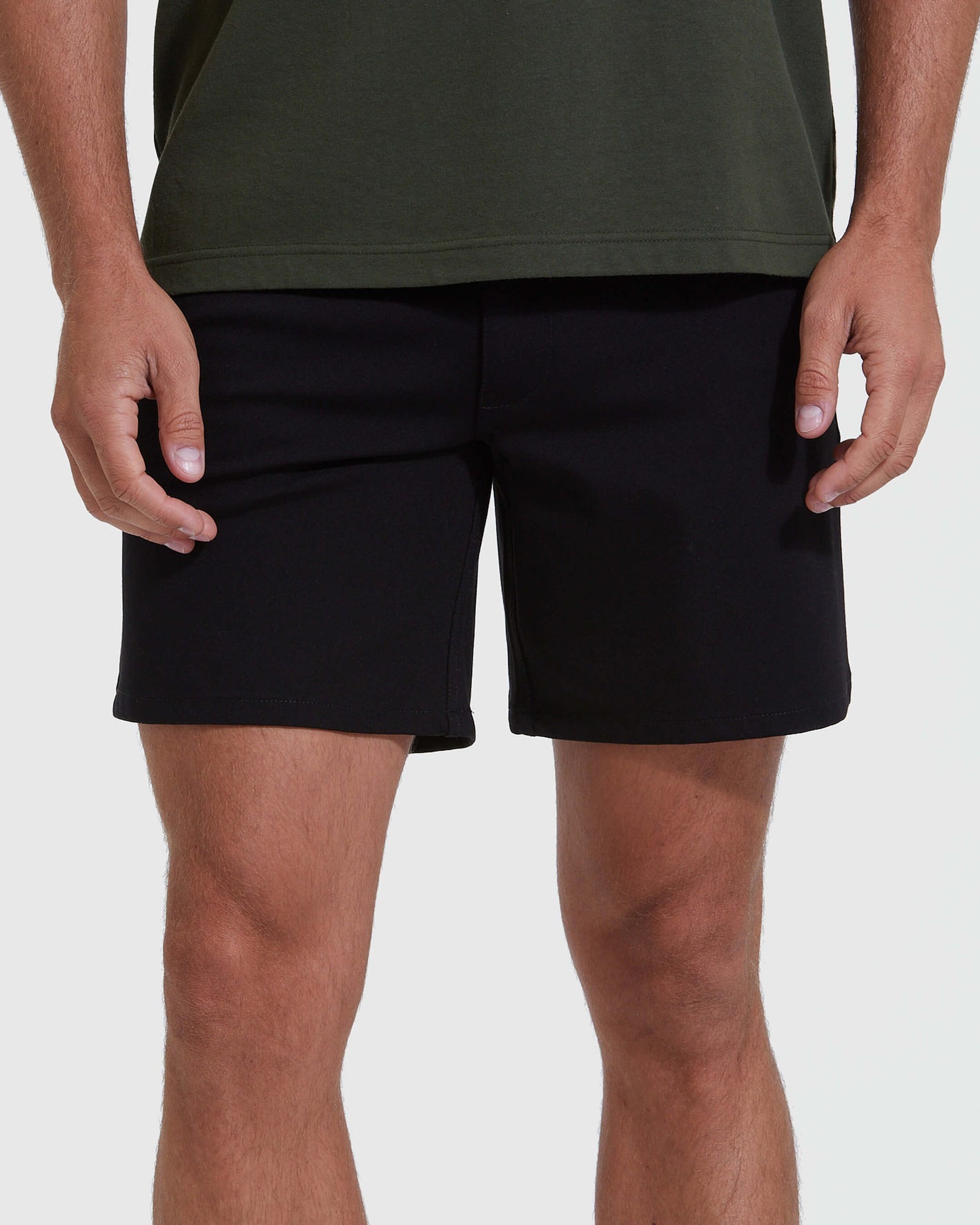 Black Commuter Short on model, mid-thigh cut, hands at sides.