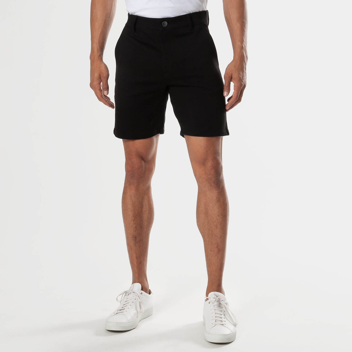 7 Black Comfort Knit Chino Shorts with side pockets and white sneakers.