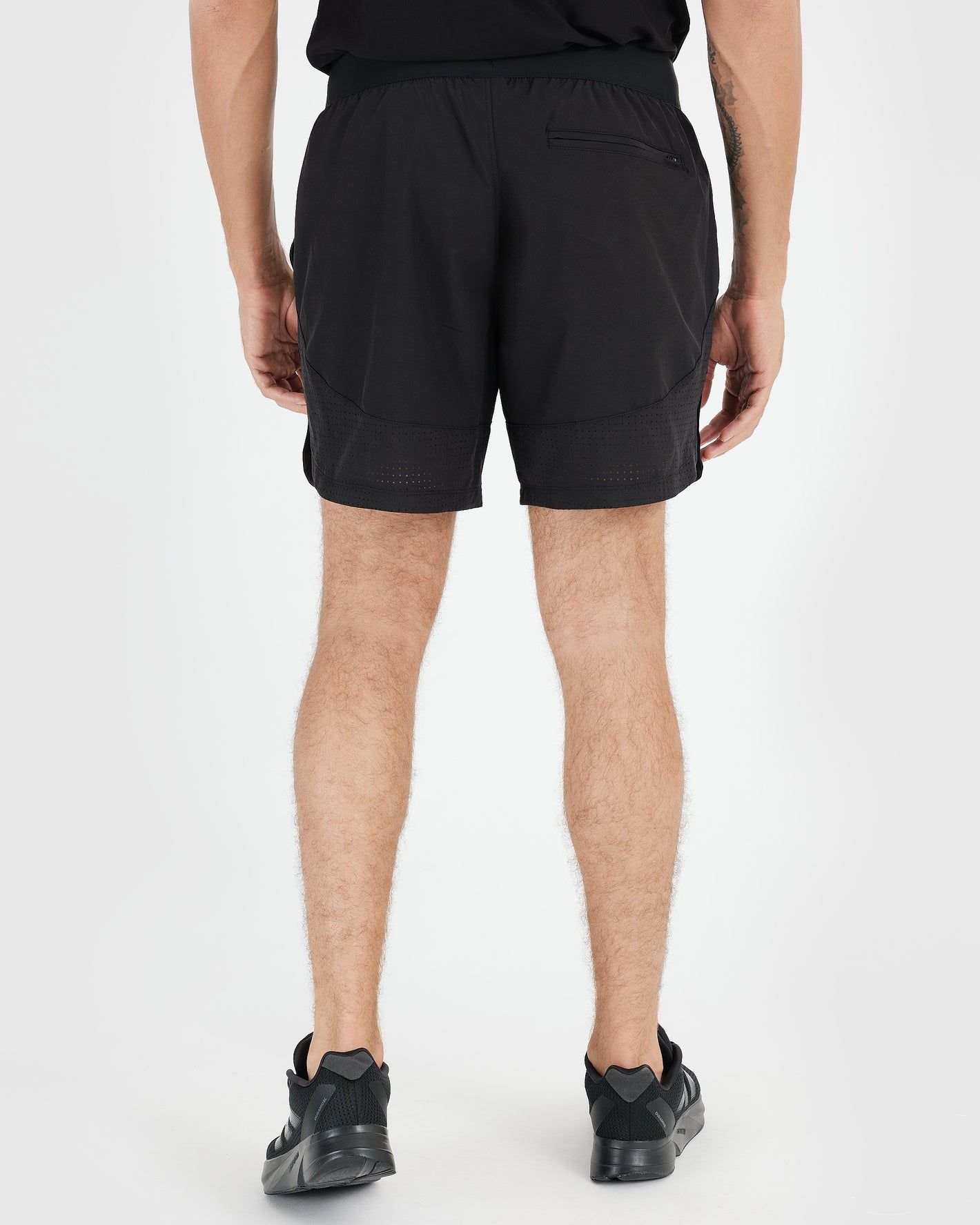 7 Black Active Training Shorts 2.0 with zippered pocket, worn by standing individual.