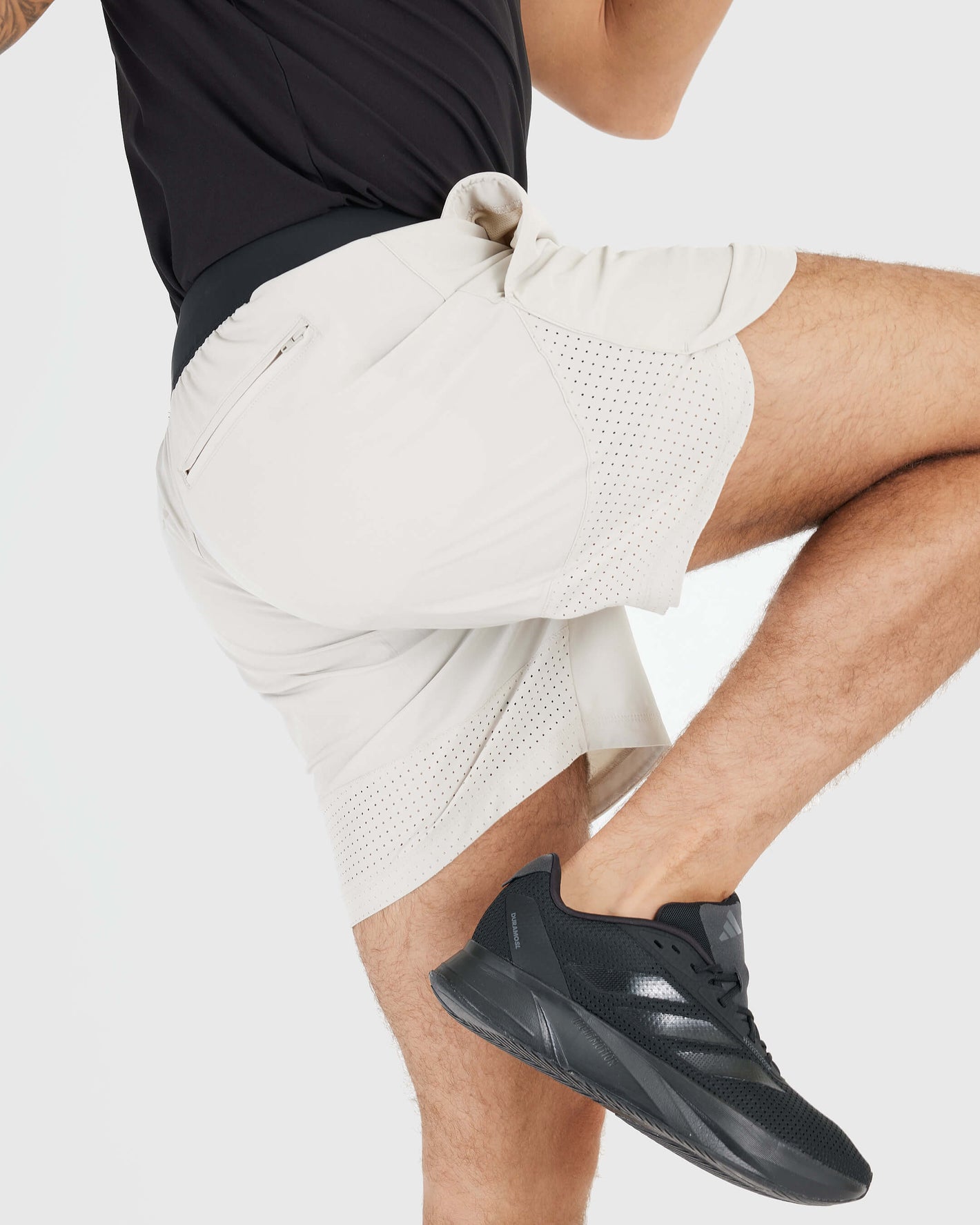 7 Sandstone Active Training Short with zip pocket and black running shoes.