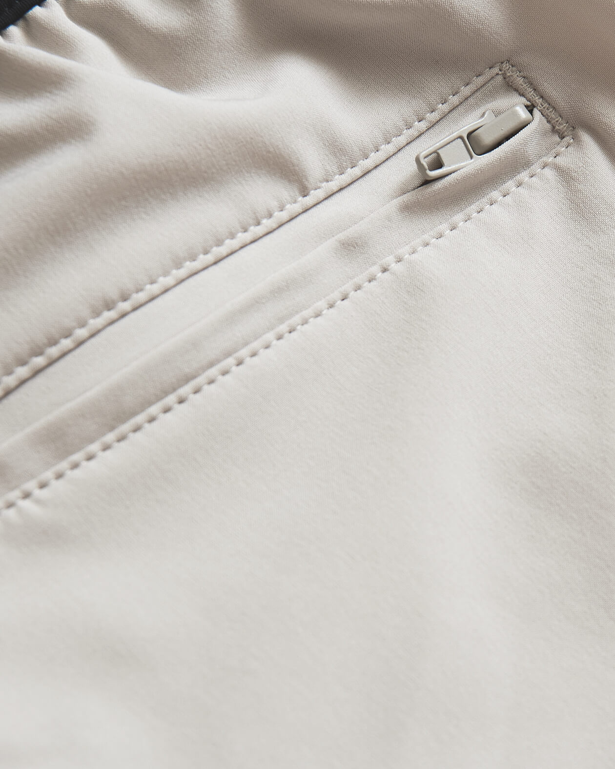7 Sandstone Active Training Short's light-beige zippered pocket detail.