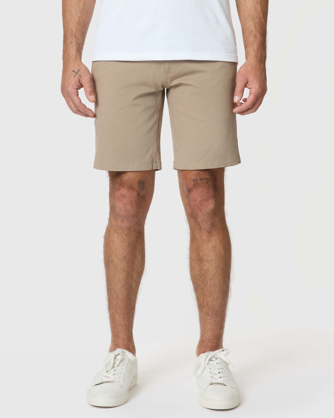 Man wearing Khaki Twill Short, white sneakers, visible knee tattoos.