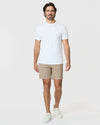 Man wearing 7 Khaki Classic Twill Shorts, white T-shirt, sneakers.