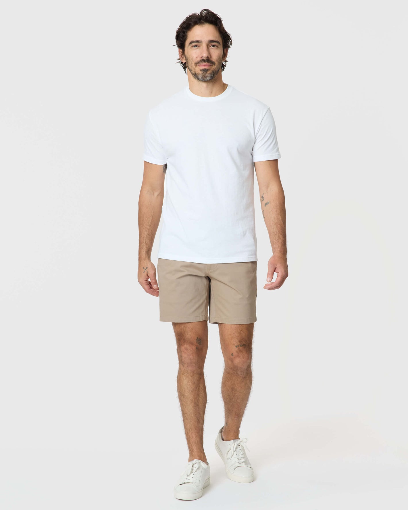 Man wearing 7 Khaki Classic Twill Shorts, white T-shirt, sneakers.