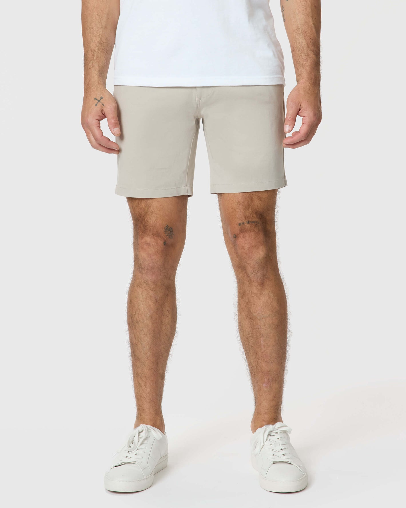 Man wearing 7 Sandstone Classic Twill Shorts, white sneakers.