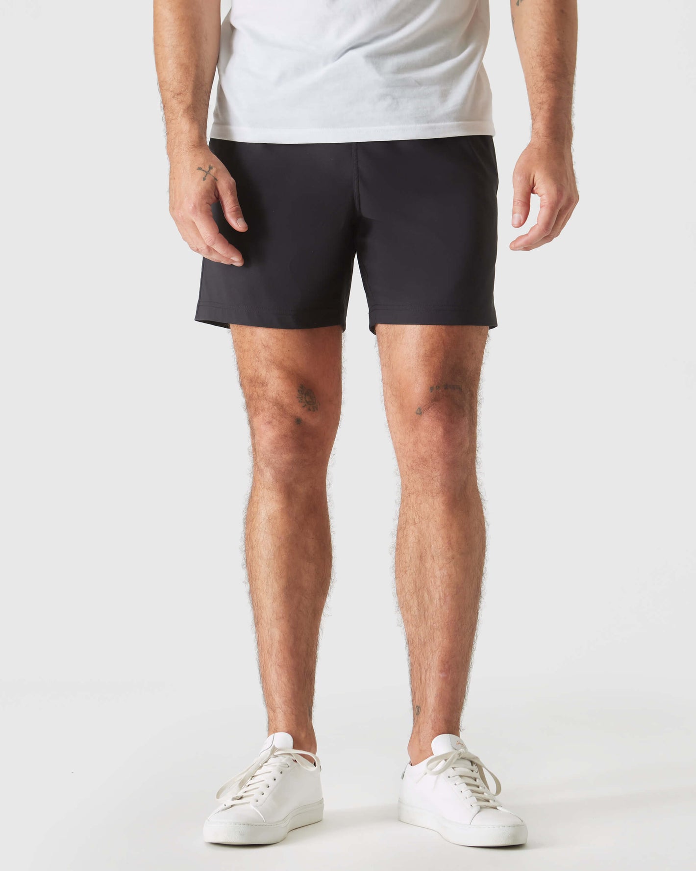 Black Swim Trunk, athletic style, with sneakers and small visible tattoos.
