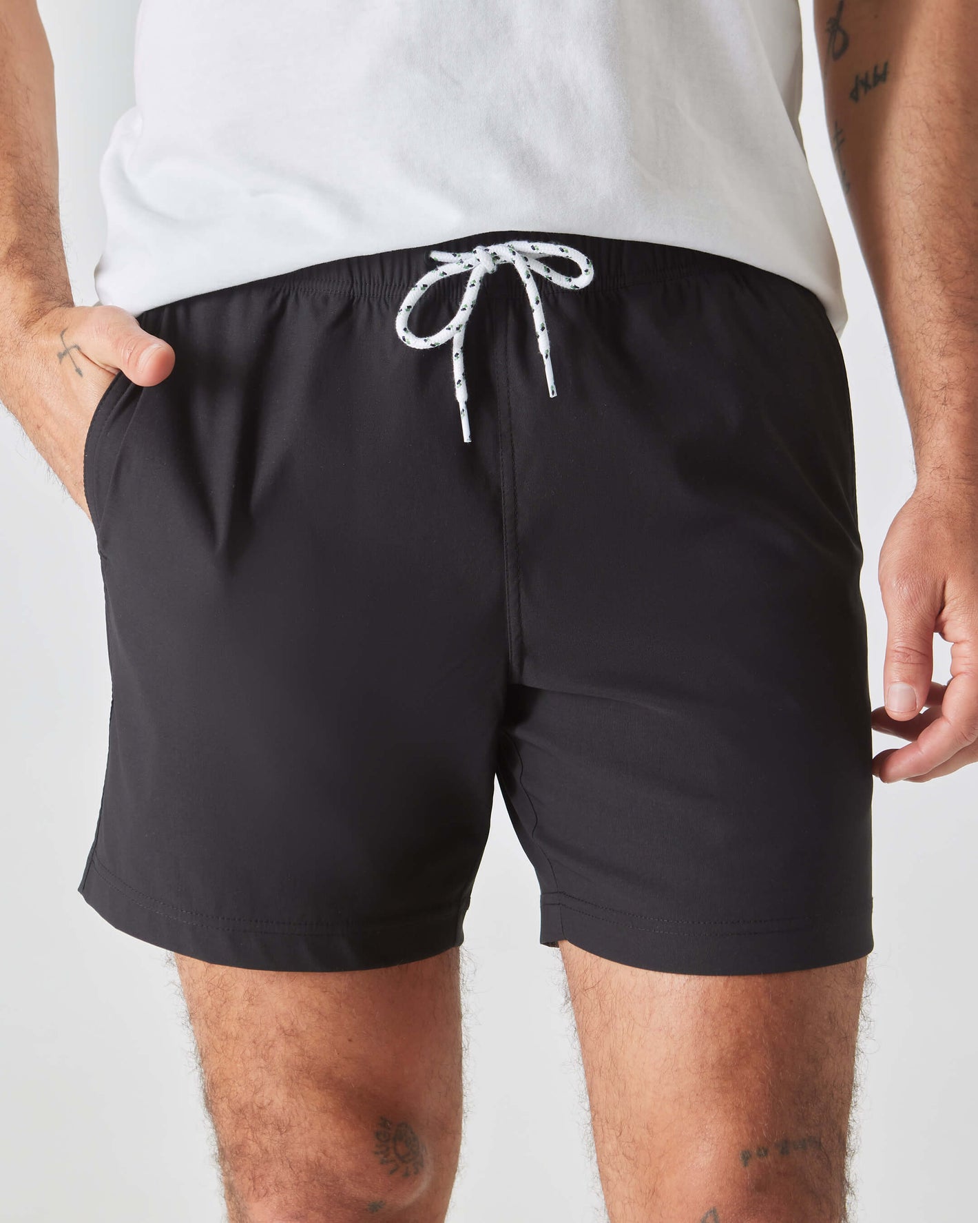 Black Swim Trunk with drawstring, side pockets; model's hand in pocket.