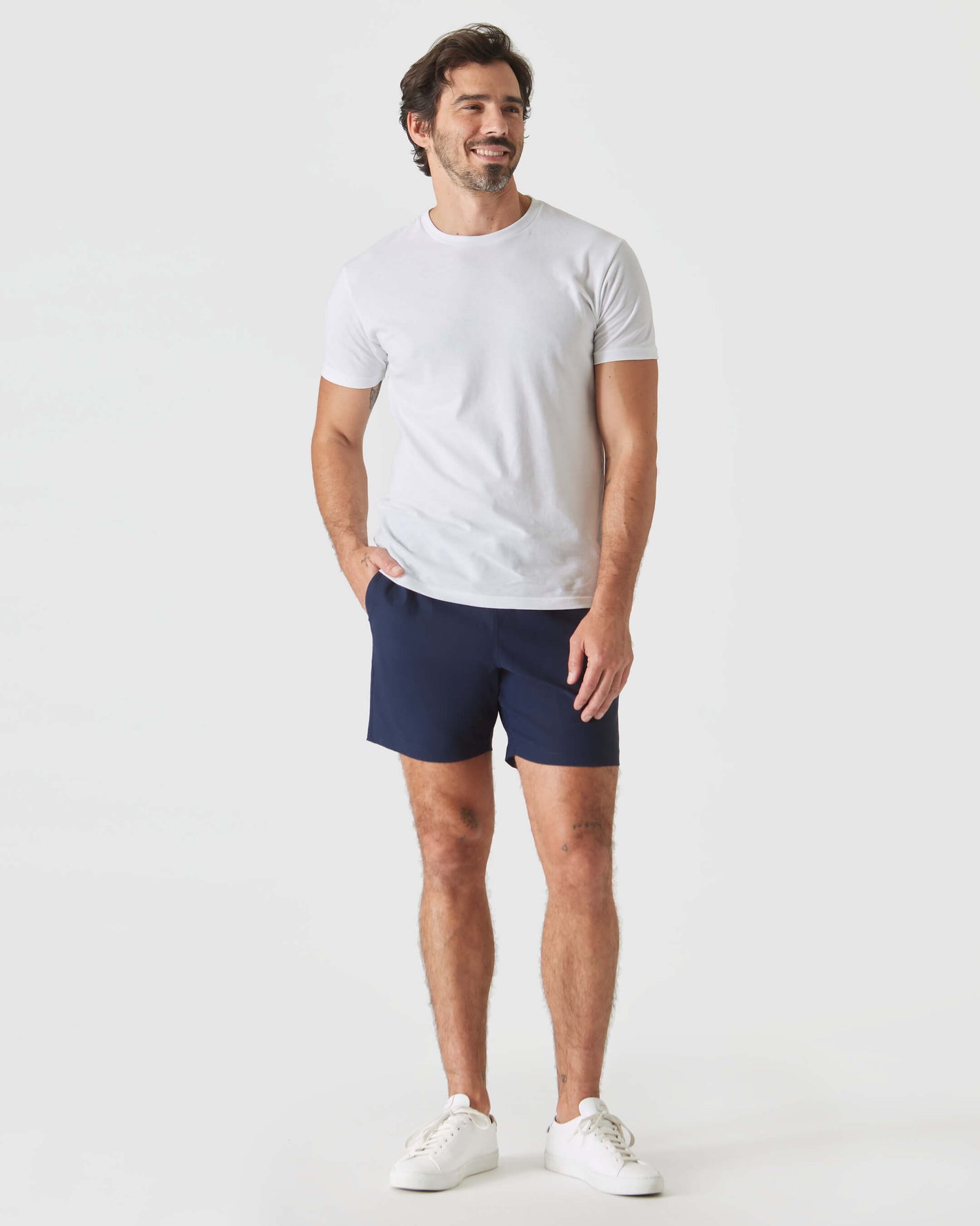 Man wearing Navy Swim Trunk, white T-shirt, and sneakers.