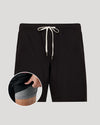 Black shorts with a drawstring on a gray background, showing a close-up of the waistband.