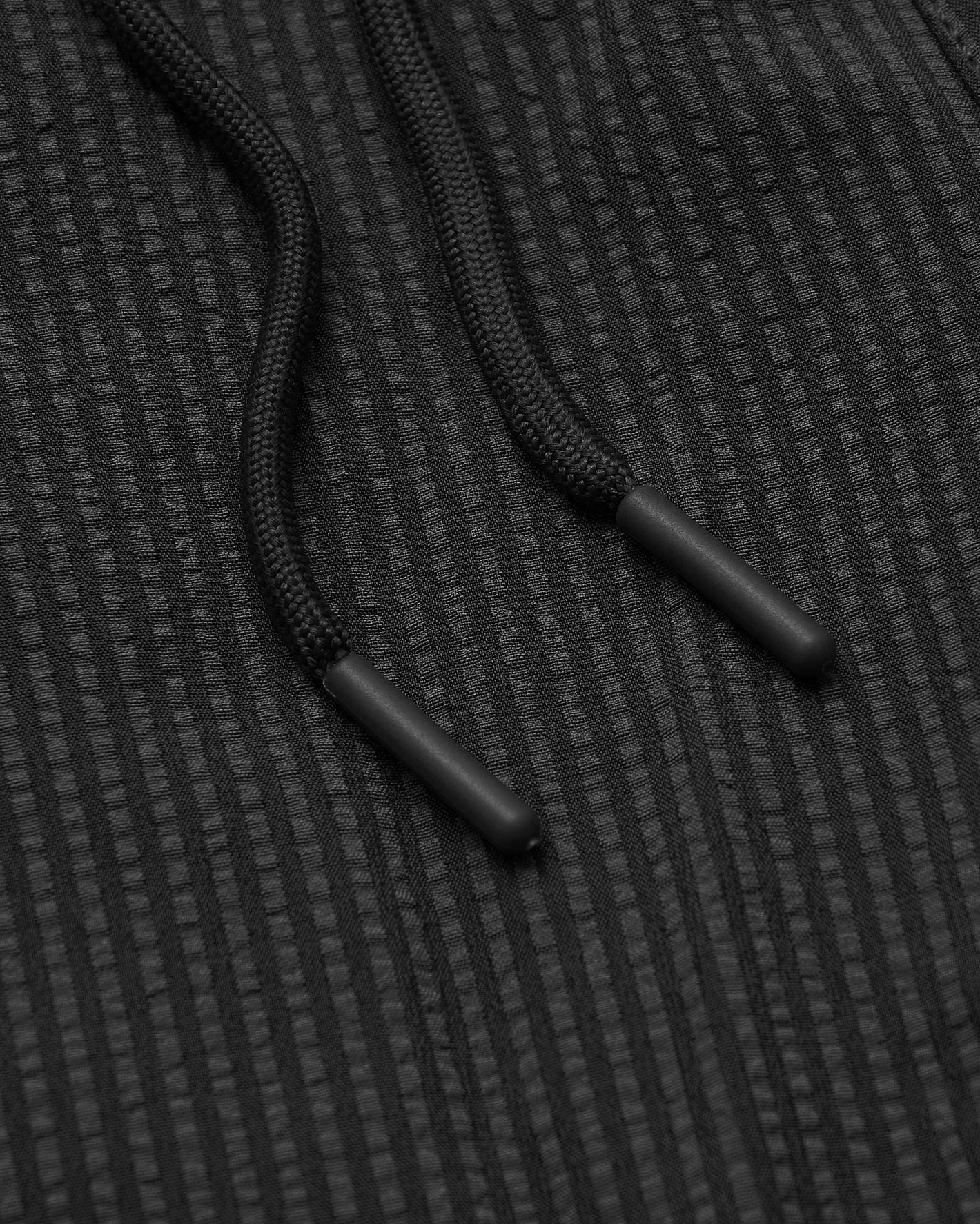 5 Smoke Seersucker Swim Trunks' black braided drawcords on textured fabric.