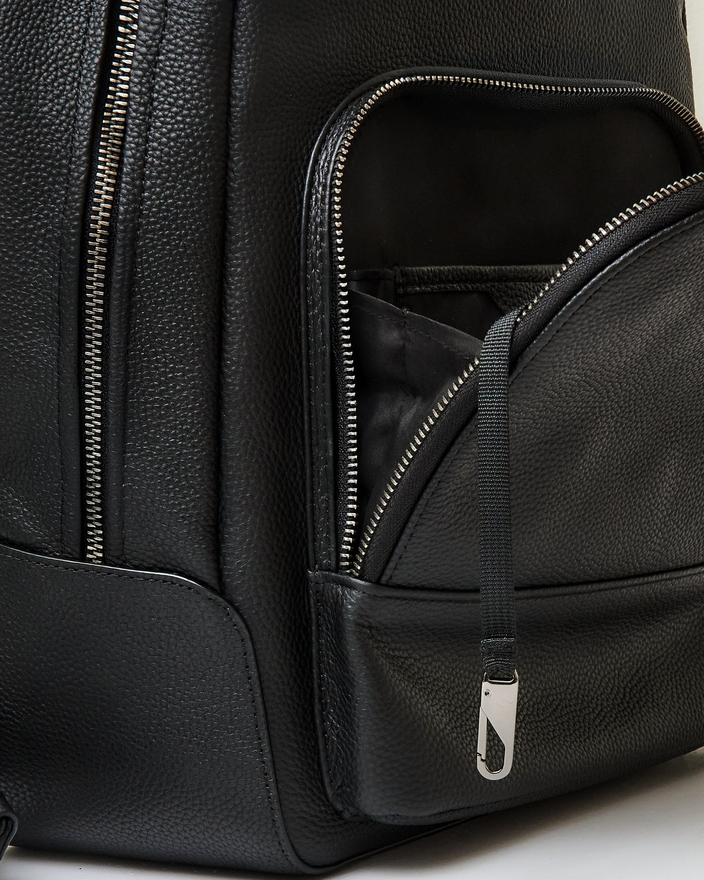 Premium Leather Backpack with pebbled texture, partially open front zippered pocket.
