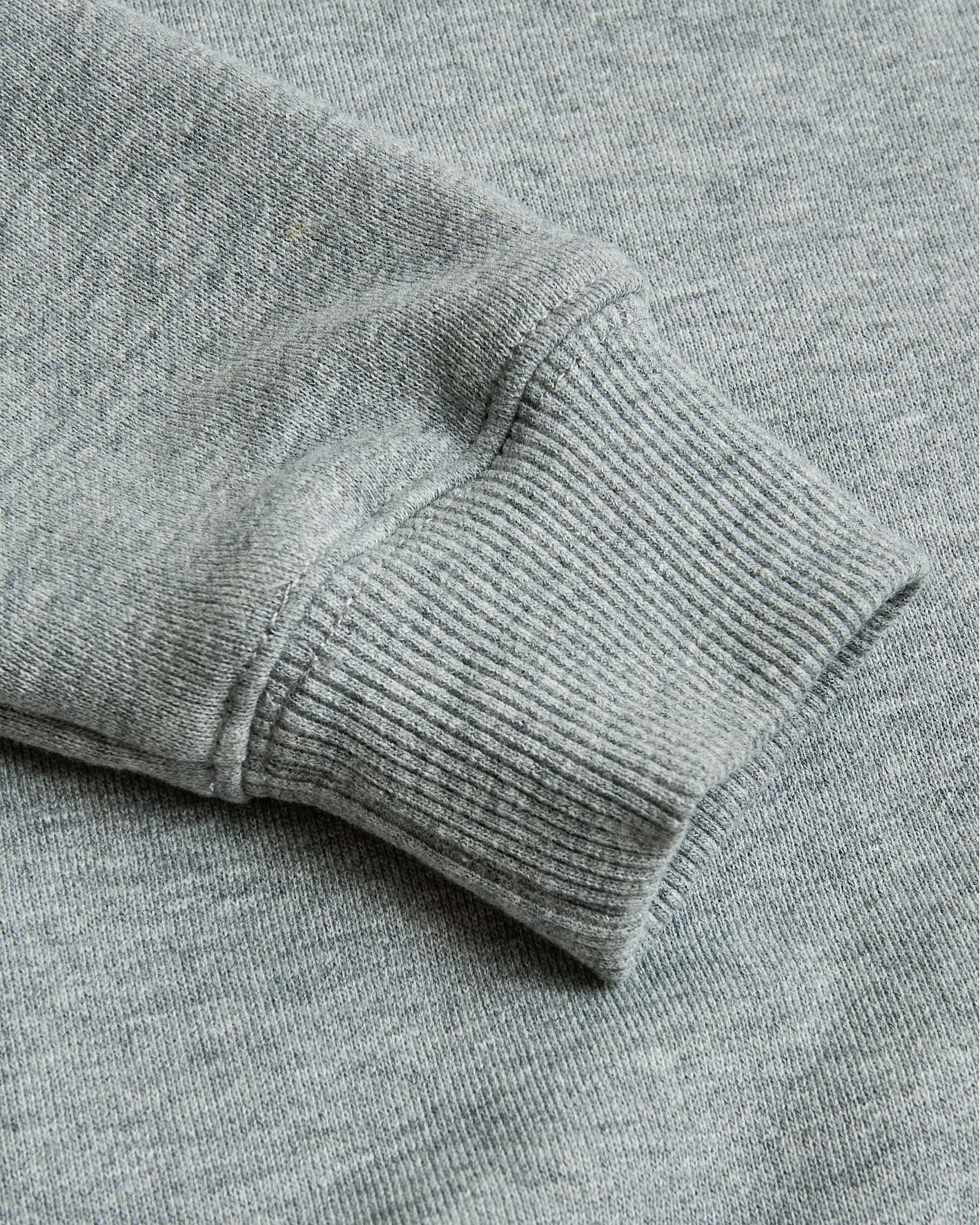 Close-up of a gray sweater sleeve on a matching fabric background