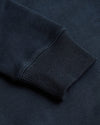 Close-up of a navy blue sweatshirt sleeve with ribbed texture.