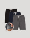 Three pairs of shorts in black, navy, and gray with drawstrings on a light gray background.