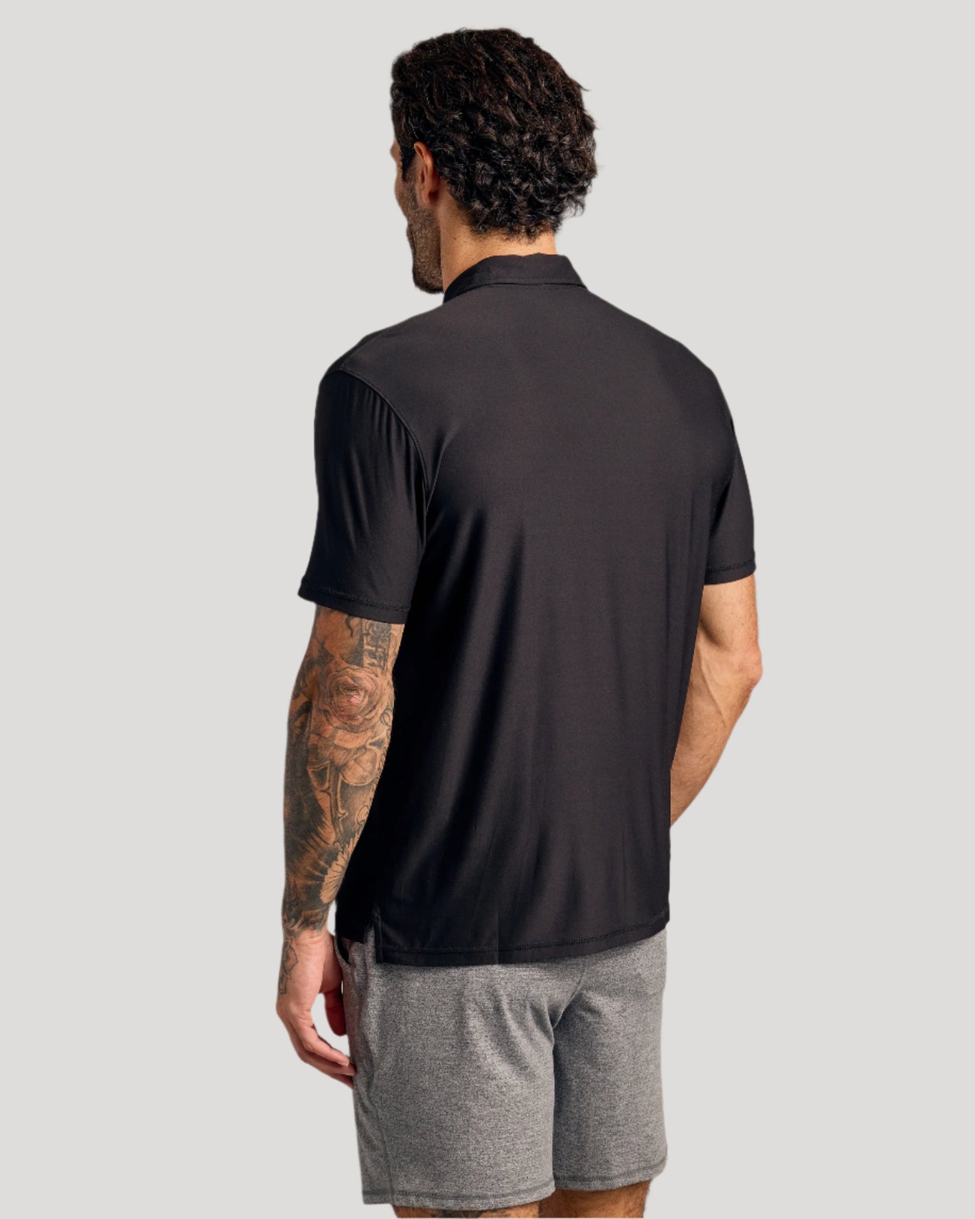 Black Active Polo 6-Pack on man, showcasing back view and tattooed arm.