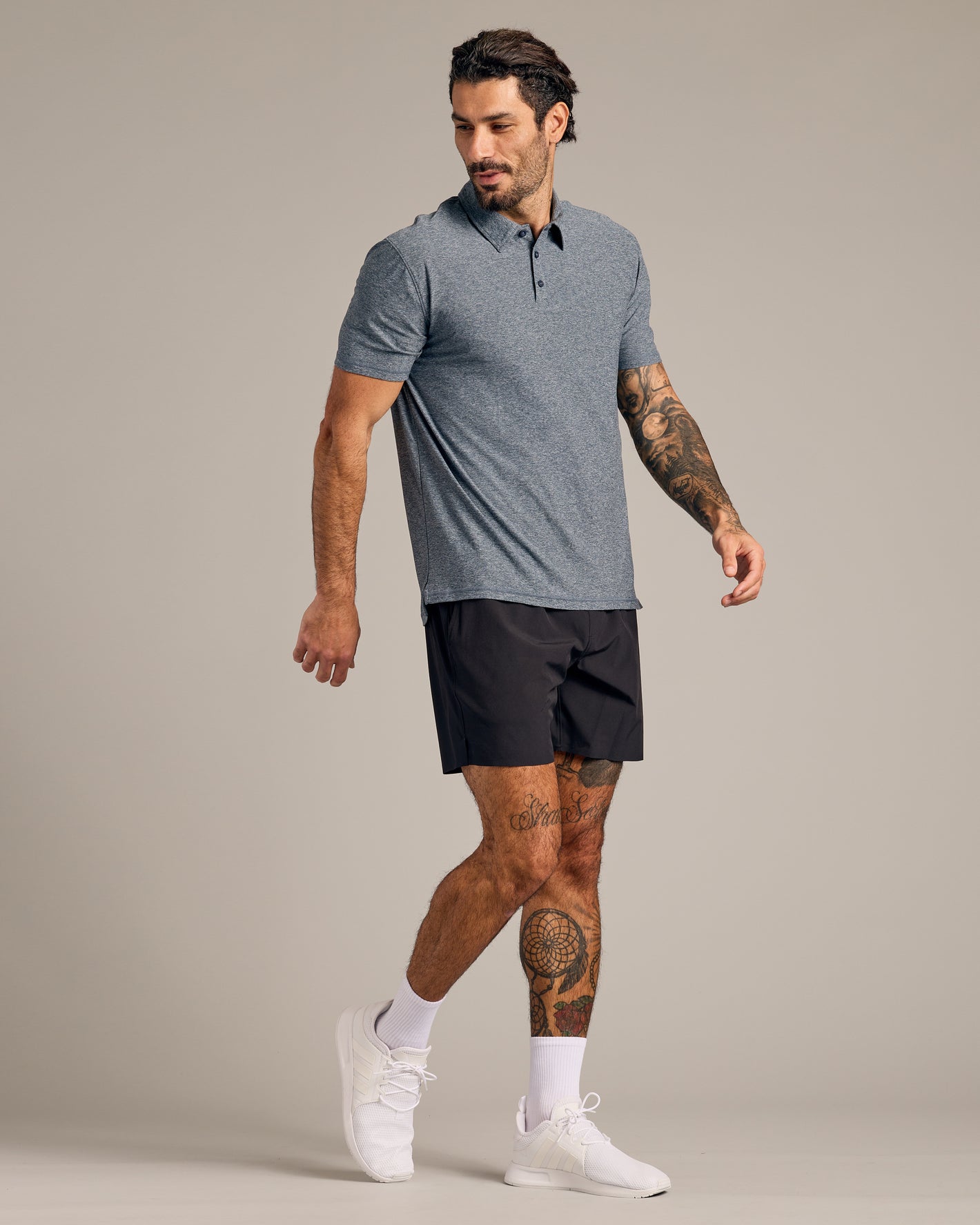 Model wearing Heather Navy Short Sleeve Active Polo, showcasing athletic fit and tattoos.