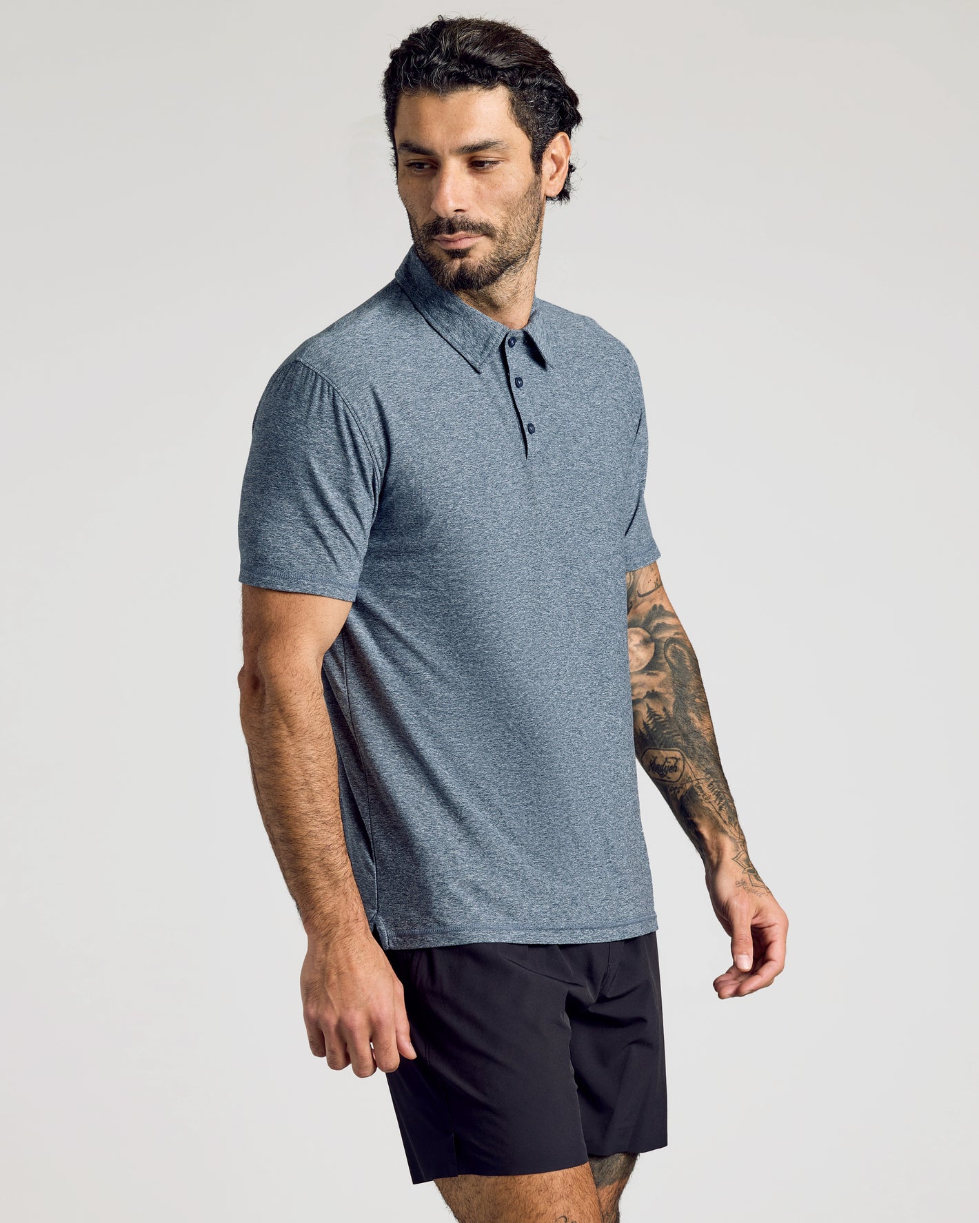 Man wearing Heather Navy Active Short Sleeve Polo and black athletic shorts.