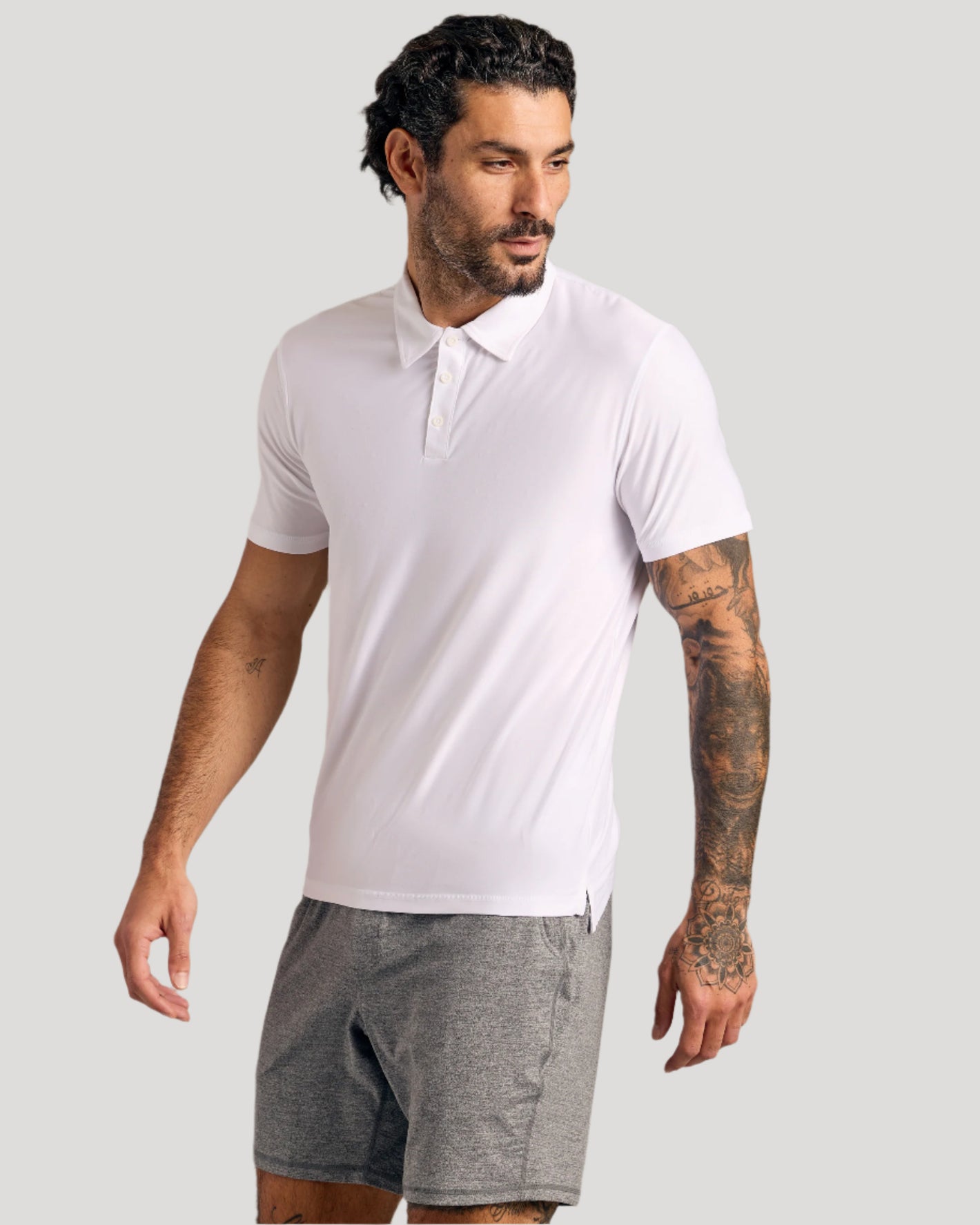 Model in The Staple Active Polo, white, with athletic shorts.
