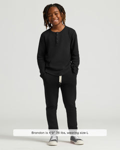 True ClassicBoy wearing Boys' Waffle Long Sleeve Henley 6-Pack, smiling with hands in pockets.