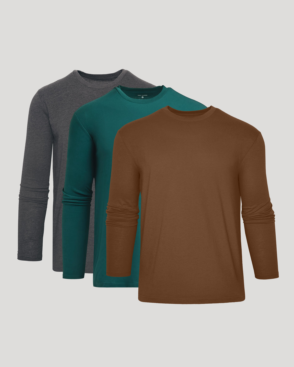 Three long-sleeve crewneck shirts in gray, teal, and brown, arranged in a layered stack against a light gray background.