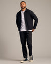 Male model in Black Coaches Jacket, open over white tee, slim-fit trousers, sneakers.