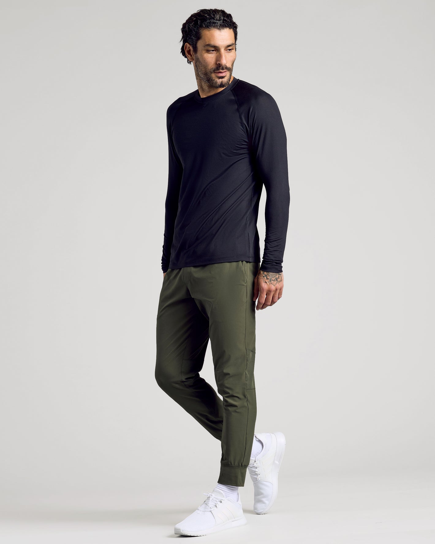 Model in Black Long Sleeve Active Mesh Crew, olive joggers, white sneakers.