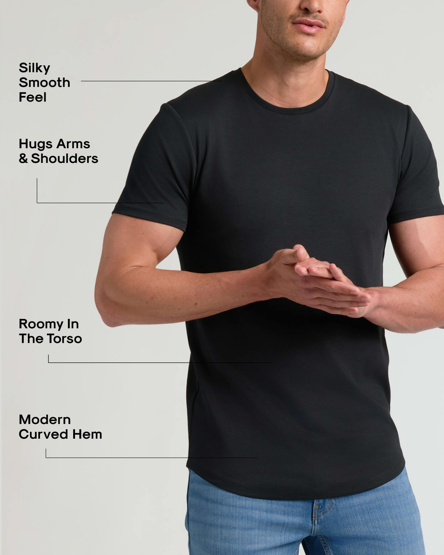 Man wearing black Tall Pima Cotton Blend Curved Hem Crew 4-Pack shirt highlighting silky smooth feel, snug fit on arms and shoulders, roomy torso, and modern curved hem, paired with blue jeans.