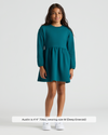 Girl in Girls Deep Emerald Long Sleeve Fleece Dress with sneakers.