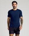 Man wearing Navy Active Mesh Raglan Tee, showcasing tattoos and relaxed stance.