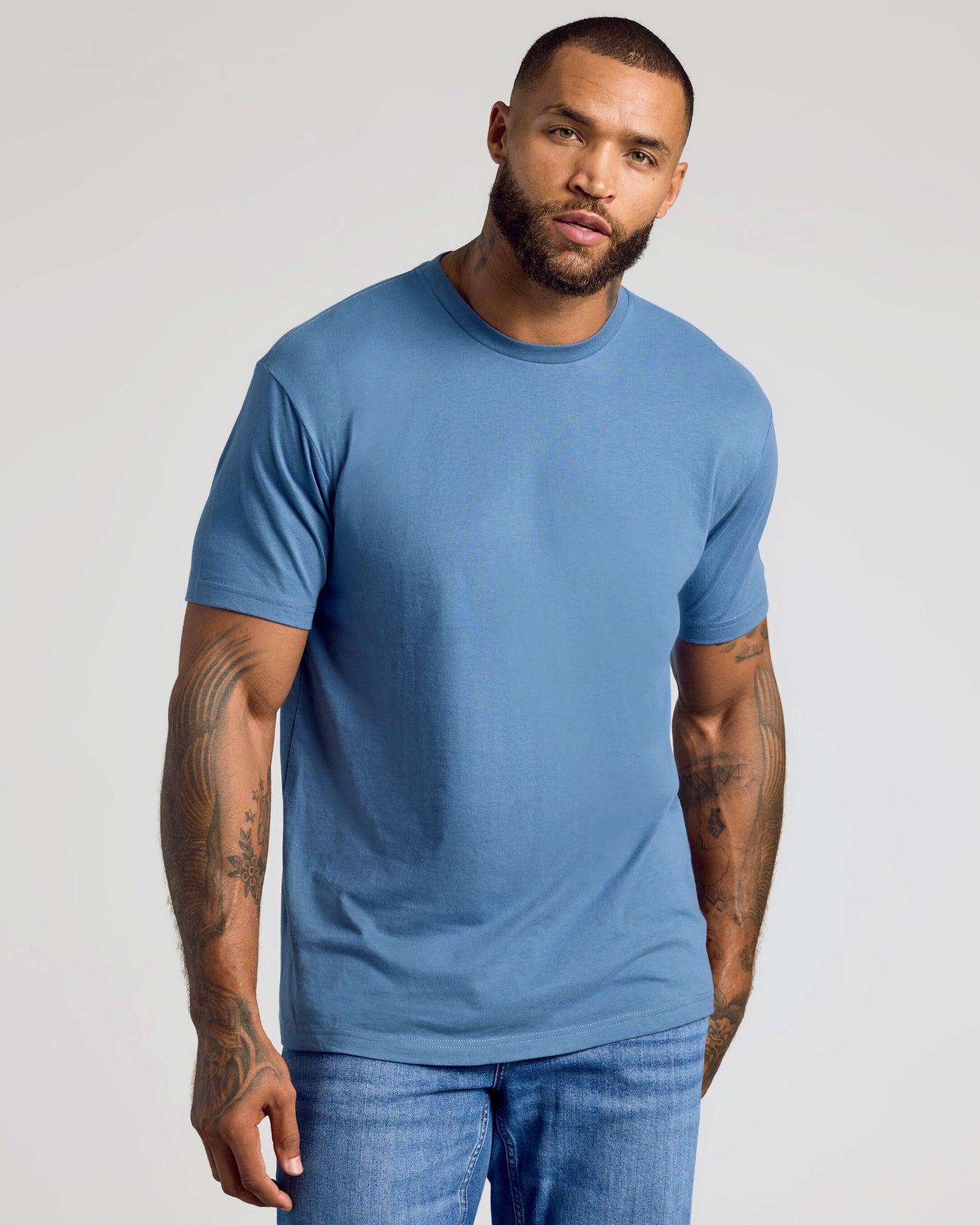 Man wearing CombinedListingTest Classic Crew Neck, medium-blue T-shirt, tattoos visible.