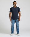 Man wearing a navy t-shirt and blue jeans on a white background. MODEL_INFO: Model is 5'8" wearing size M short