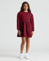Girl in burgundy fleece dress from Girls Dark Maroon & Deep Emerald Long Sleeve Fleece Dress 2-Pack.