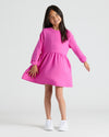 Girl in pink Girls Long Sleeve Fleece Dress, smiling with sneakers.