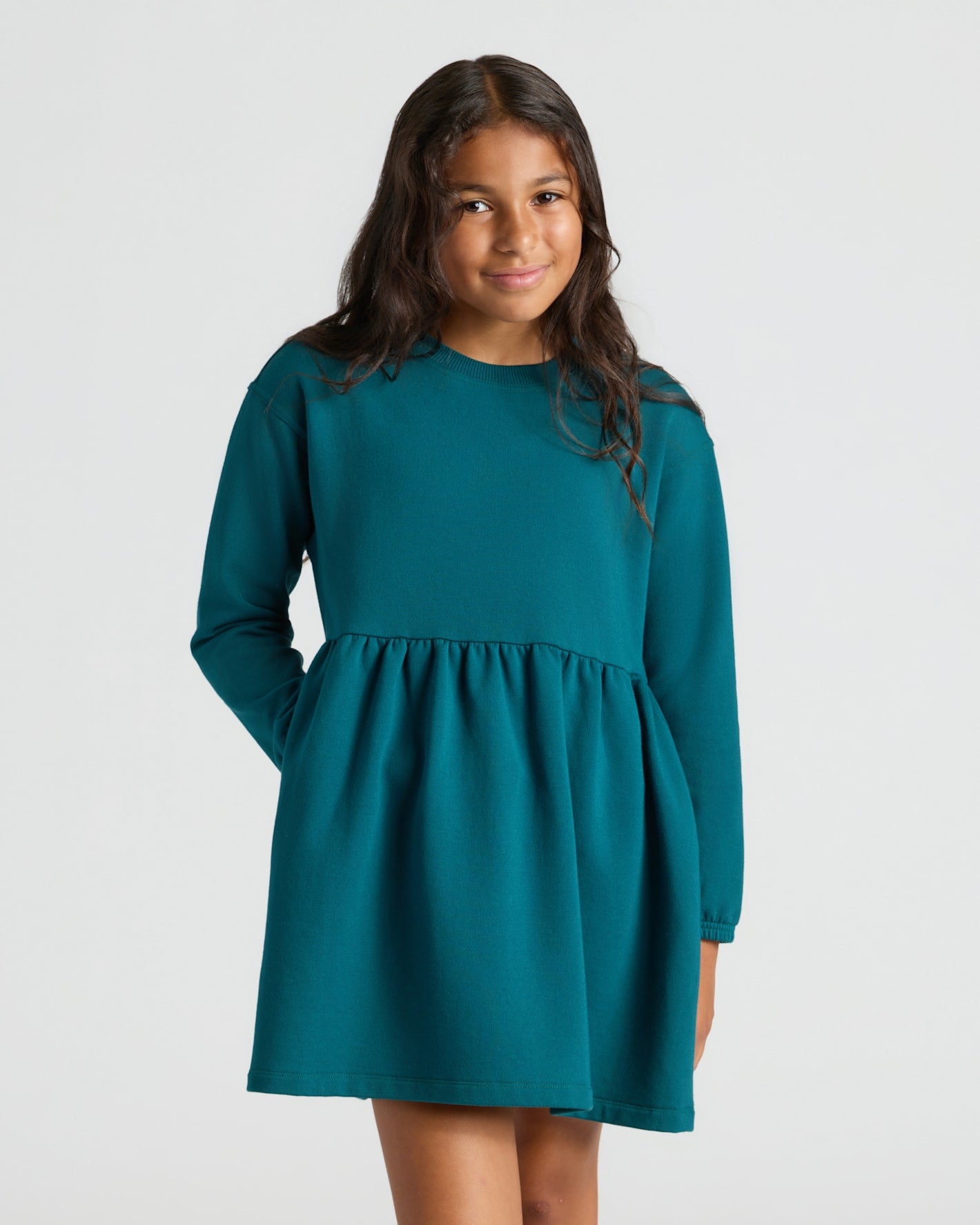 Girl in Girls Deep Emerald Long Sleeve Fleece Dress, smiling gently.