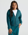 Girl wearing Girls Deep Emerald Cropped Zip Hoodie, smiling gently.
