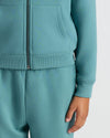 Person in teal tracksuit with Girls Stormcloud Cropped Boxy Crew Neck Tee underneath.