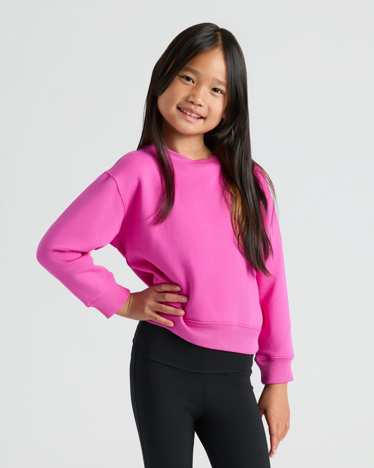 Girl wearing Girls Electric Fuchsia Slouch Pullover Crew, hand on hip, smiling.
