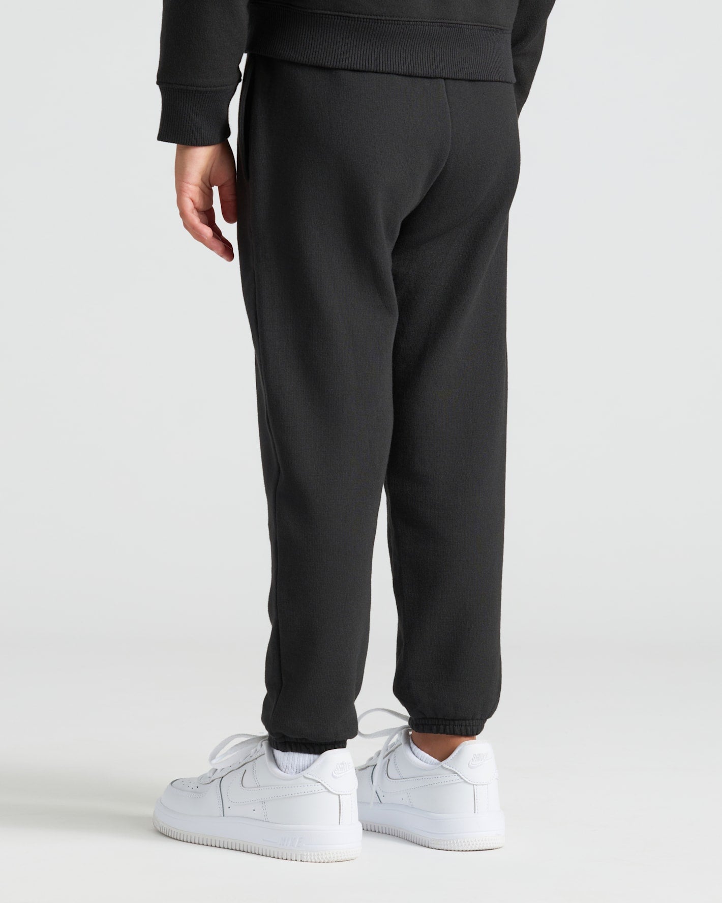 Child wearing Girls Deep Emerald & Black Relaxed Joggers, showcasing elastic cuffs.