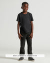 Boy in Boys' Black Classic Curved Hem Crew Neck, black pants, gray sneakers.