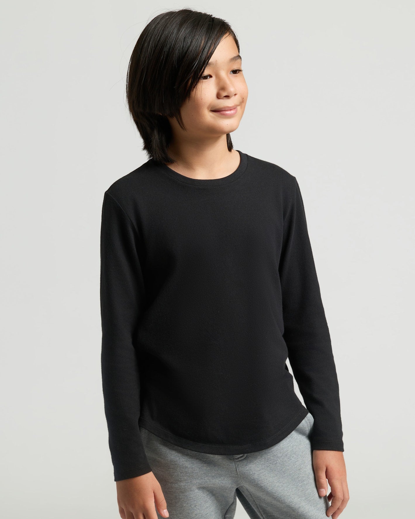 Young boy wearing Boys' All Black Classic Long Sleeve Curved Hem Crew Neck.