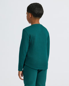 True ClassicChild in Boys' Waffle Long Sleeve Henley, teal-green, jogger pants, back view.
