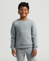 Child wearing a gray sweatshirt and pants on a light gray background