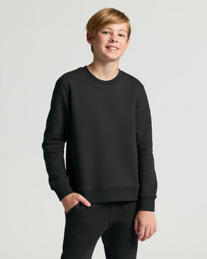 Young person wearing a black sweatshirt on a light gray background