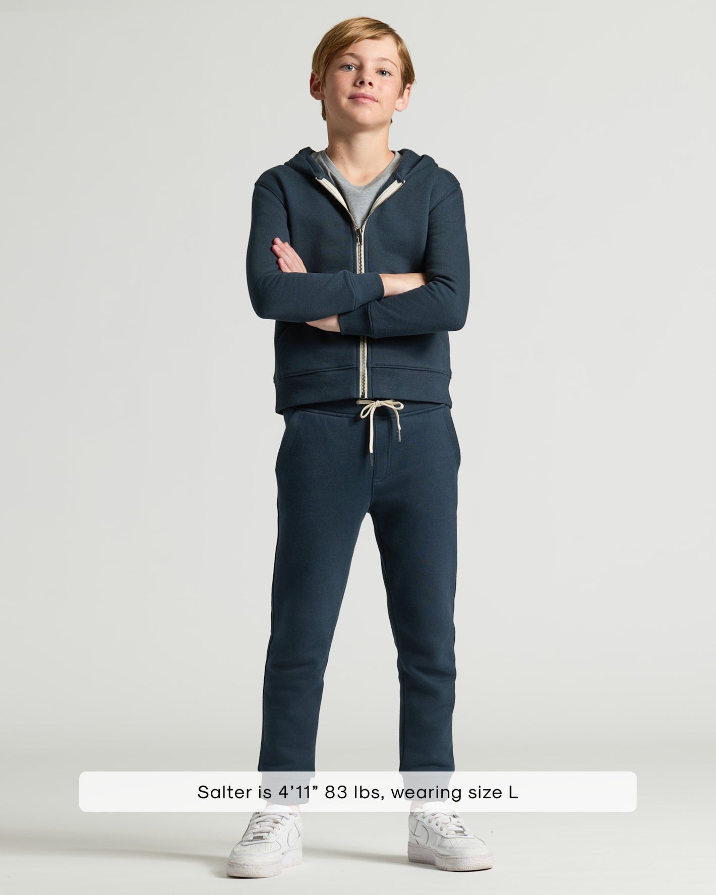 Boy wearing Boys' Navy Fleece Jogger, navy hoodie, gray T-shirt, white sneakers.